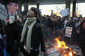 Students protest: A girl warms herself by a fire as student protesters clash