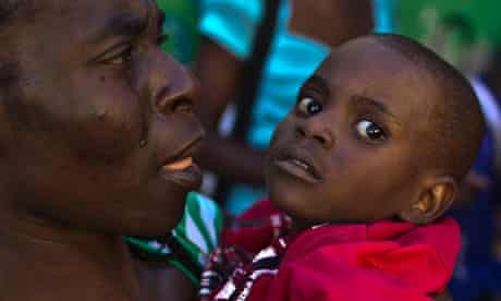 A woman carries a child with symptoms of cholera in Port-au-Prince