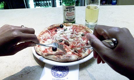A customer eating a pizza at the London Wall branch of the Pizza Express restaurant chain.