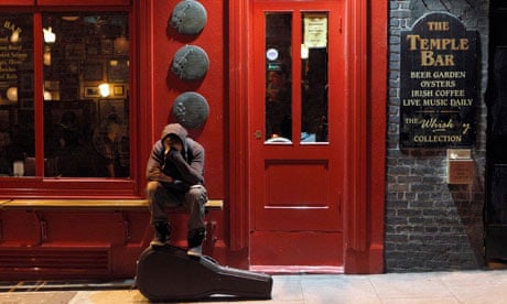 A musician sits on a bench outside a pub in Temple Bar, Dublin
