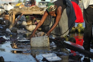 Haiti Cholera: A woman collects water from the ground in downtown Port-au-Prince