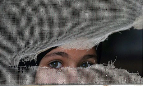 Palestinian refugee girl looks out from her parents home at Refugees camp