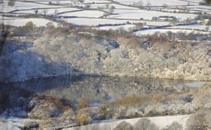Weather Update: Reflections of snow covered trees are seen in a lake near Sutton Bank