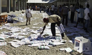 Haiti Elections: man picks up ballots after frustrated voters destroyed electoral material