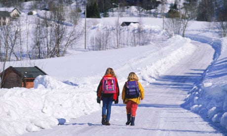 Two school children with backpacks on country road in winter in Scandinavia