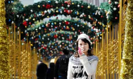A woman talks on her mobile phone under Christmas decorations in Shanghai