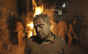 Shia Ashura Update: A Shia man covered in mud stands near a fire to dry during Ashura Iran