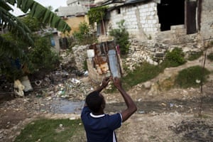 Haiti Cité Maxo: A Haitian attempts to wire electricity cables in Cité Maxo