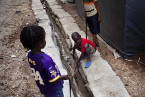 Haiti Cité Maxo: Children play in an improvised water canal at the camp settlement Cité Maxo