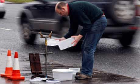A man fills plastic containers with water from a standpipe in Belfast