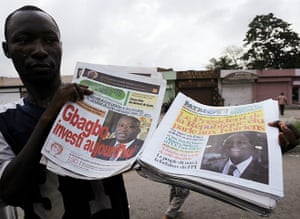 Ivory Coast: A man holds newspapers bearing headlines