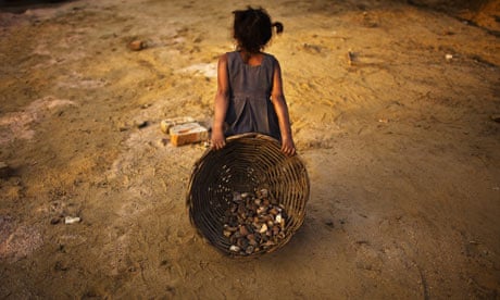 A young girl carries a basket of stones on a building site in in New Delhi, India