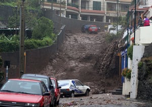 Madeira : People look on as mud and water rush down a street in Funchal 