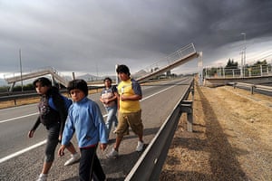 Chile Earthquake: People walk along a highway with a collapsed bridge in Santiago