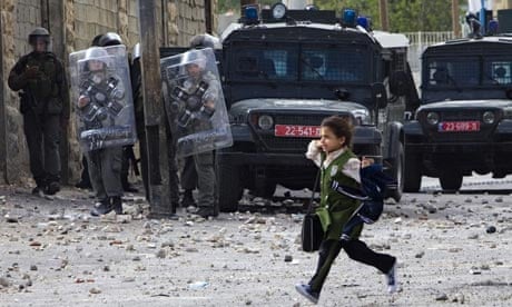 A girl runs past Israeli troops  during clashes with Palestinians in East Jerusalem yesterday