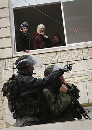 24 Hours in Pictures: Palestinian women watch as Israeli policemen take position near Ramallah