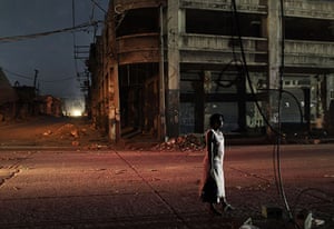 24 Hours in Pictures: A woman waits for a bus in Port-au-Prince as darkness falls over the city
