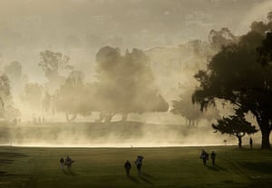 24 Hours in Pictures: Golfers walk the first fairway after a delay due to mist of the Kia Classic