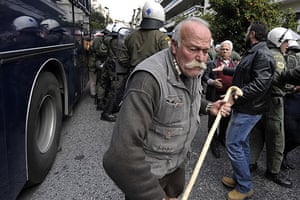 Greece protests: A Greek pensioner walks past a riot police, Athens Greece