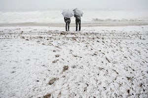 24 hours in pictures: Barcelona, Spain: A couple walk on the beach during a snow storm