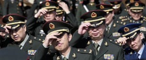 24 hours in pictures: Beijing, China: Military delegates hold their hats against the wind