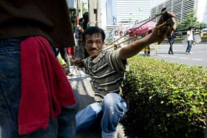 Thailand protests: An anti-government protester fires a slingshot at military forces