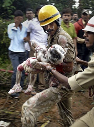 24 Hours in Pics: Indian firefighters carry a survivor out of the Air India plane crash