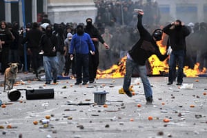 Greek riots dog: 6 December 2009: A demonstrator throws a stone at riot police 