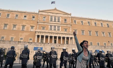 A woman shouts anti-government slogans in front of  riot police outside parliament in Athens