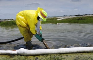 Deepwater Horizon: BP oil spill: A clean-up worker uses a suction hose to siphon-up oil