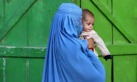 A woman wearing burqa carries a child th