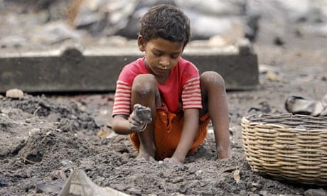 An Indian boy breaks coal at a waste dump near Kolkata