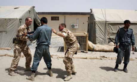 British soldiers train an Afghan police oﬃcer at the British army base Task Force Helmand
