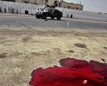 US soldiers drive past a pool of blood from a car bomb in Baghdad during October 2006