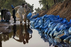Pakistan Flood Update: Men place sand bags to re-enforce a levee in Pakistan