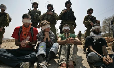 West Bank separation protesters sit in front of Israeli troops in Bil'in 