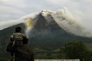 Sinabung volcano: A man and his son look as the Sinabung volcano spews thick smoke