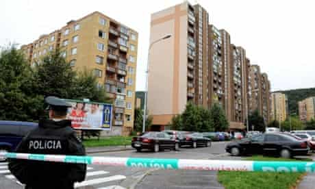 A police officer stands guard near the block of flats in Bratislava where a gunman killed six people