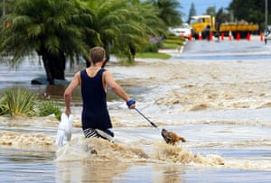 Queensland floods: A man struggles with his dog through floodwaters in the town of Dalby