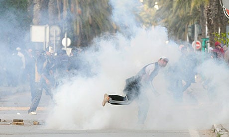 A Tunisian demonstrator throws a rock after police fired tear gas during demonstrations in Tunis