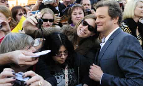 Actor Colin Firth poses with a fan at a