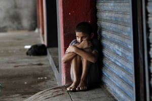 24 hours: Manzanillo, Mexico: A boy takes shelter from the rain in front of a store