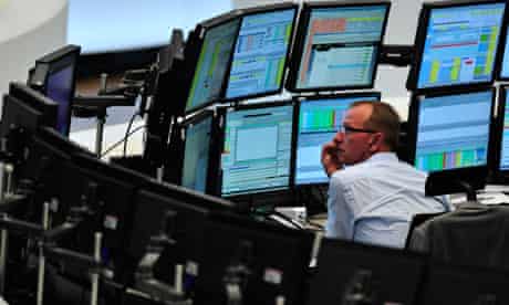 A trader sits in front of screens showing the German DAX index in Frankfurt