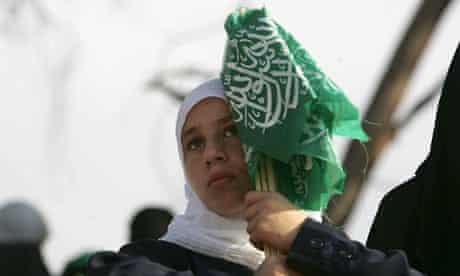 A Palestinian girl holds Hamas flags