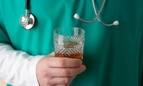man wearing medical scrubs and stethoscope holding glass of hard liquor alcohol