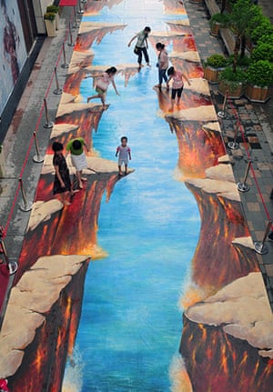 3D pavement art: 17 July 2011: People play on a 3D street painting at Wanda Square in Fuzhou