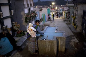All saints day: A woman fills a jug with water for flowers to decorate graves, Guatemala
