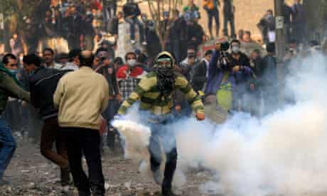 Protester runs away from tear gas thrown by police in Cairo, Egypt