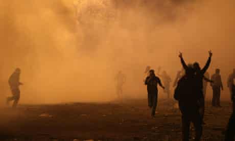 Egyptian protesters flee a barrage of teargas as they clash with riot police near Tahrir Square