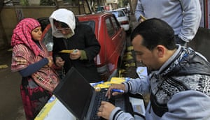 Egypt elections: Egyptian voters wait as a voting official checks their identity information